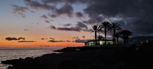 a house on the beach with palm trees and a sunset at ALMar We Go! Habitaciones privadas en Alcalá - Private Rooms - Pièces privées - Stanza privata in Alcalá