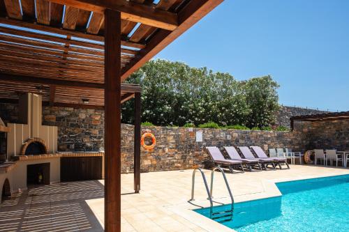 a house with a swimming pool and a patio at Maris Villas in Elounda