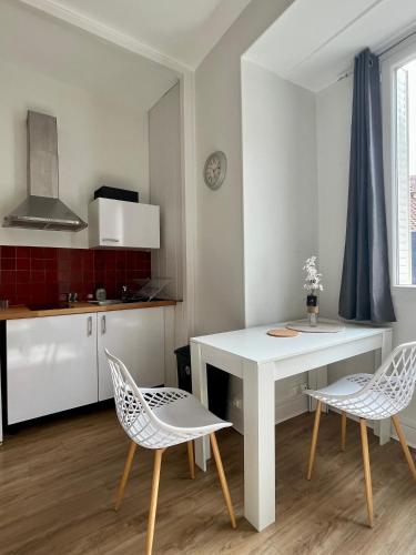 une cuisine avec une table blanche et deux chaises dans l'établissement Appartement Vichy - Hyper Centre, à Vichy