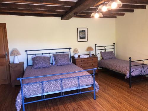 two beds in a room with wooden floors at Domaine du Roucou in Nabirat