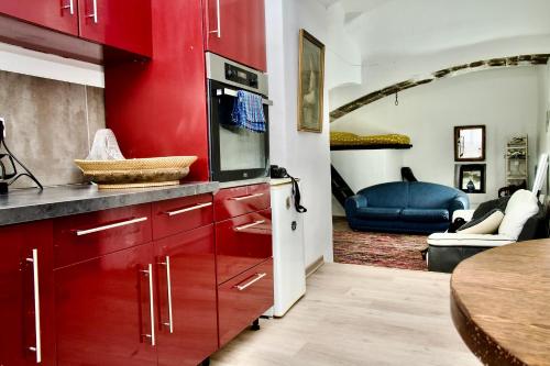 a kitchen with red cabinets and a living room at Appartement Sauve pour quatre personnes in Sauve