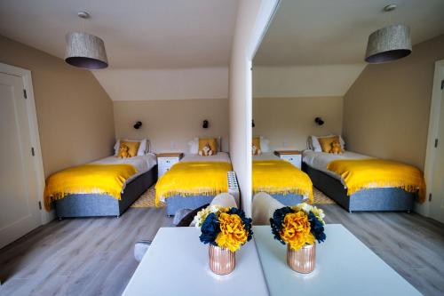 a room with three beds with yellow pillows and flowers at 9 Parklands Holiday home in Killarney