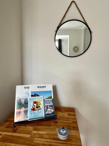 a mirror on a wall above a table with a table sidx sidx sidx at Appartement Vichy - Hyper Centre in Vichy