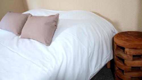a white bed with a pillow and a wooden table at La Sapinière St Lary Soulan in Saint-Lary-Soulan