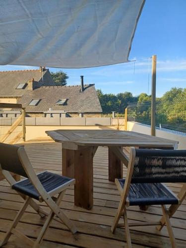 une table et deux chaises sur une terrasse avec un parasol dans l'établissement Maison de ville - terrasse sud, a 10 min des plages, à Saint-Brieuc