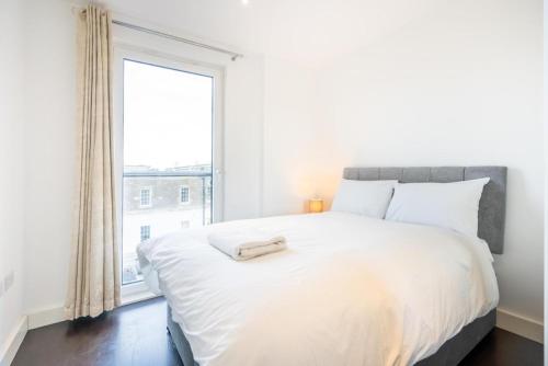 a bedroom with a large white bed with a window at Superb 2 bed 2 baths Apartment in Woolwich