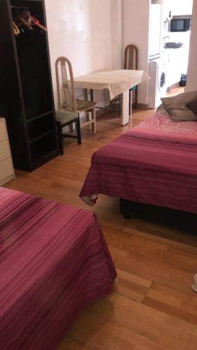 a room with two beds and a table and chairs at Pandiellos II in Madrid