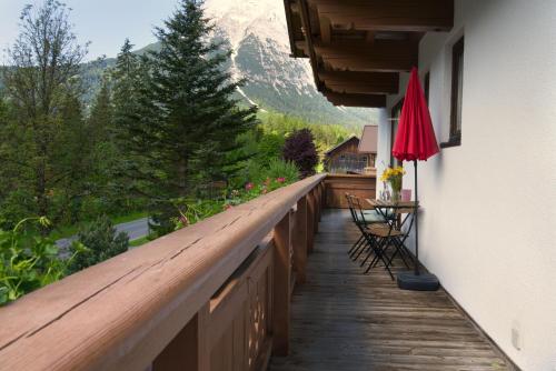 a wooden balcony with a table and chairs and a mountain at Haus Almrose in Leutasch