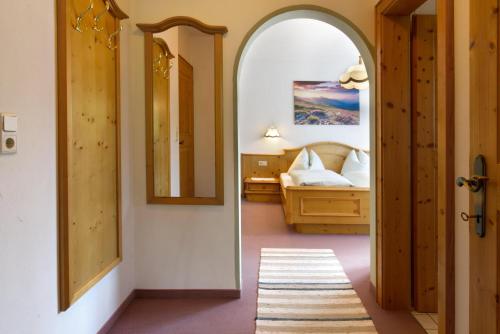 pasillo con dormitorio con cama y espejo en Haus Almrose, en Leutasch