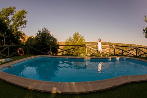 a woman standing by a fence next to a pool at Casas Cueva Cazorla in Hinojares