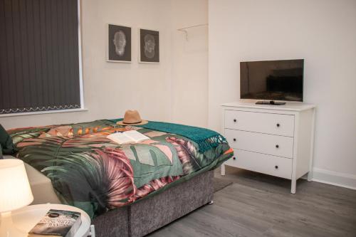 a bedroom with a bed and a dresser and a television at Warm and relaxing hideaway in Aintree