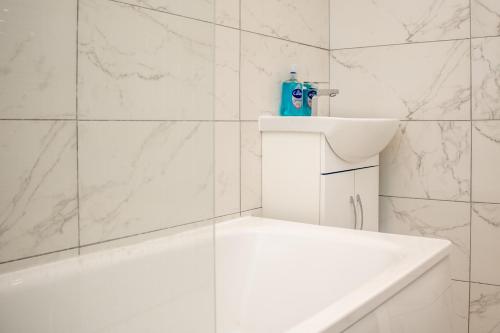 a white bathroom with a white tub and a sink at Warm and relaxing hideaway in Aintree