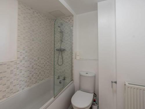 a white bathroom with a shower and a toilet at 3rd Floor Apt Near QMC Hospital with City Views in Nottingham