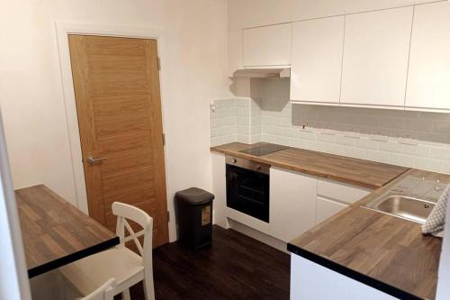 a kitchen with white cabinets and a sink and a table at Ovidio's House - Peaceful flat with Terrace Relax in London