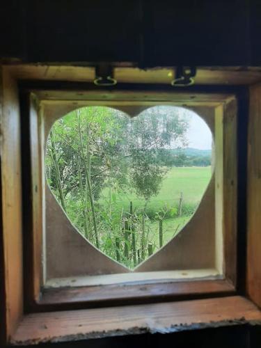 a heart shaped window with a view of a field at Off grid Rosie Sheperd hut and summerhouse plus 1 acre at Tanyrallt in Llanybyther