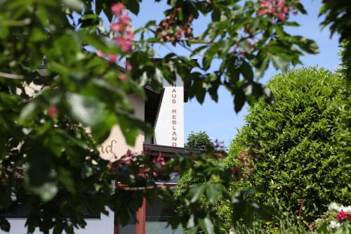 a white sign on top of a building with trees at Hotel Restaurant Haus Rebland in Baden-Baden