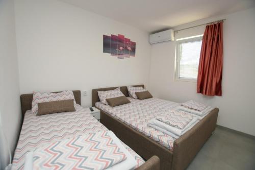 two beds sitting in a room with a window at Olymp Apartmani in Kladovo