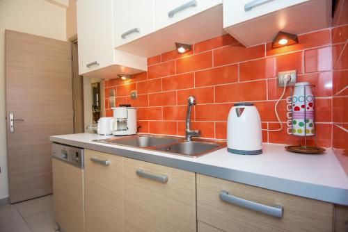 a kitchen with a sink and an orange tiled wall at Sofia's Delightful Apartment in Argostoli