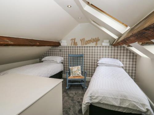 two beds in a small room with a chair at The Moorings in Wakefield