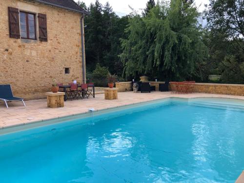 a large blue swimming pool with chairs and a house at Domaine du Roucou in Nabirat