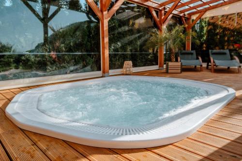 a large hot tub on a wooden deck with chairs at Morze Domków Wellness & Spa in Dziwnówek
