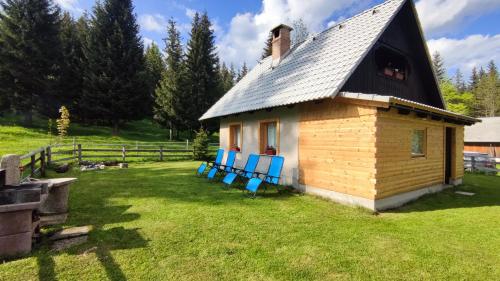 une petite maison avec des chaises bleues dans une cour dans l'établissement Triglav Cottage, à Bohinj