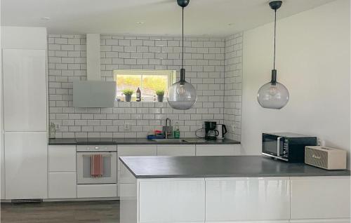 a kitchen with white appliances and two pendant lights at Stunning Home In Tingsryd With Wifi in Tingsryd