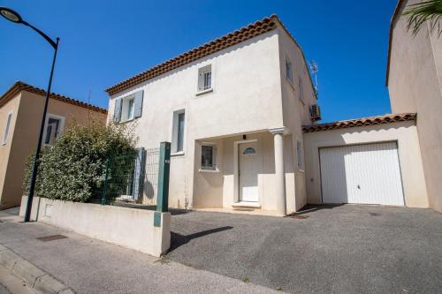 une maison blanche avec un portail et un garage dans l'établissement Bright pearl with garden near the sea, à Hyères