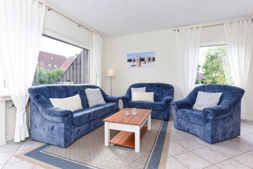 Sala de estar con 2 sillas azules y mesa de centro en Ferienwohnung Bensersiel Ahoi en Bensersiel