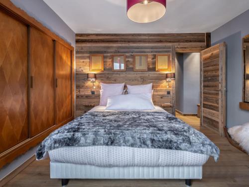 une chambre avec un lit et un mur en bois dans l'établissement Appartement rénové 5 chambres avec balcon, cheminée et Wifi à 400m du centre de Megève - FR-1-453-170, à Megève