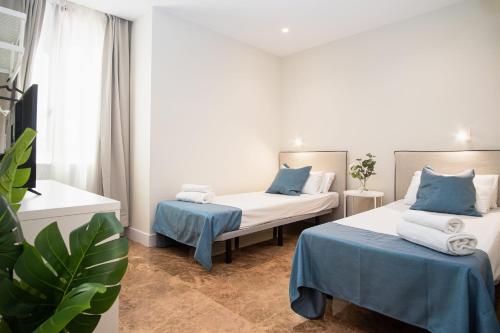 two beds in a room with blue and white at VTZ The Orus Factory Hotel - Parking Muy Económico in Zaragoza