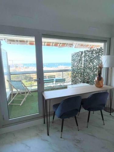 une pièce avec une table et des chaises et une grande fenêtre dans l'établissement Vue mer, climatisation, 10 min des plages, à Antibes