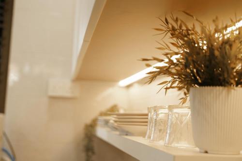 Eine Pflanze in einer weißen Vase auf einem Regal in der Unterkunft 38 villa homestay in Muar