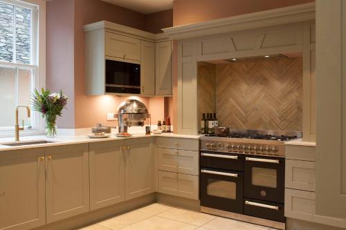 uma cozinha com armários brancos e um forno com placa de fogão em Moss Grove Organic em Grasmere