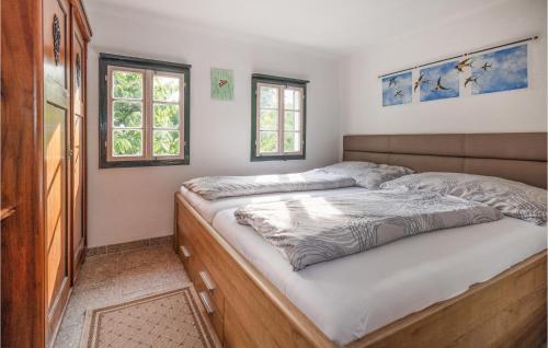 ein Schlafzimmer mit einem Bett und zwei Fenstern in der Unterkunft Amazing Home In Deutsch Schtzen With 1 Bedrooms in Deutschschützen