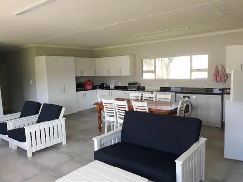 a living room with chairs and a table and a kitchen at Aandblom 5 in Stilbaai