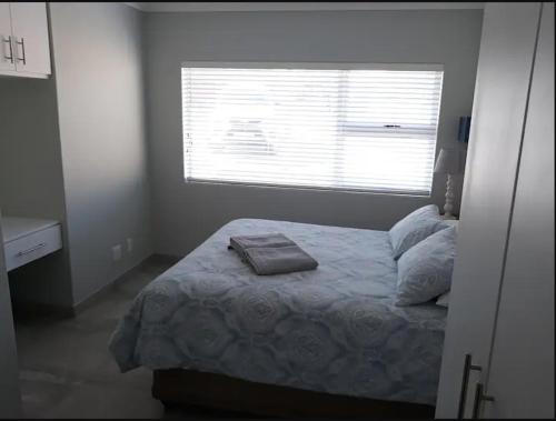 a bedroom with a bed and a window with a pillow at Aandblom 5 in Stilbaai