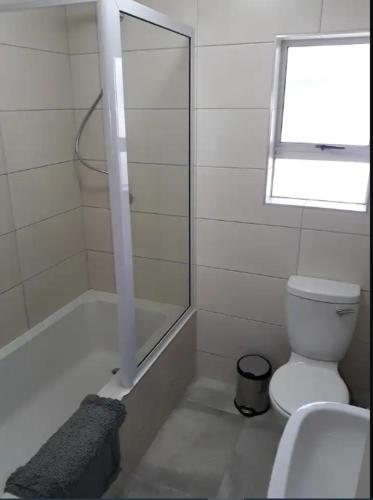 a bathroom with a toilet and a shower and a window at Aandblom 5 in Stilbaai