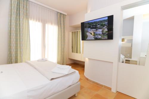 1 dormitorio con 1 cama y TV en la pared en Agave Blu, en San Nicolò