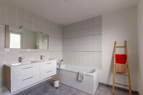 La salle de bains est pourvue d'un lavabo et d'une baignoire. dans l'établissement Les Fuchsias - Maison proche de la mer, à Asnelles
