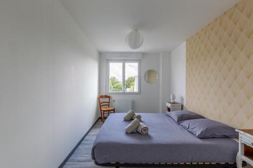 un osito de peluche sentado en una cama en un dormitorio en Les Fuchsias - Maison proche de la mer, en Asnelles