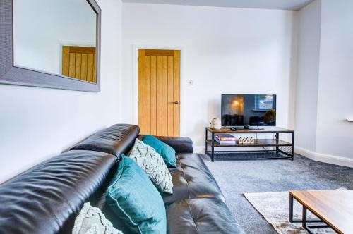 sala de estar con sofá de cuero y mesa en Pass the Keys Beautiful large modern house in Southend en Southend-on-Sea