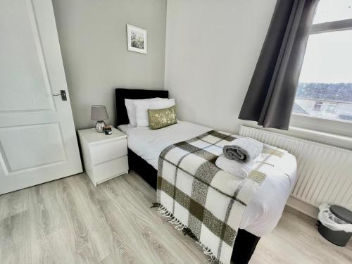 um pequeno quarto com uma cama e uma janela em Executive 3 bedroom Port Talbot Town Centre Margam Sleeps 7 em Taibach