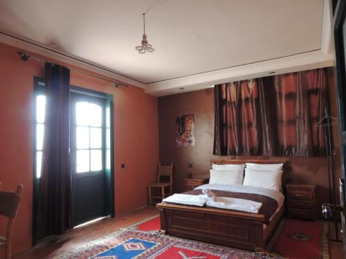 um quarto com uma cama com paredes cor de laranja e uma porta em Auberge Kasbah Amoun em Taliouine