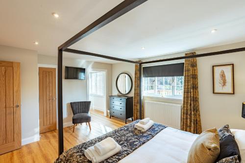 a bedroom with a large bed and a chair at Sparrowhawk Cottage with Hot Tub in Newton Stewart
