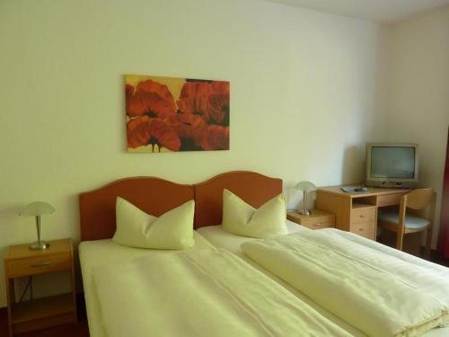 a bedroom with a bed and a desk with a television at Hotel Grüner Jäger in Travemünde
