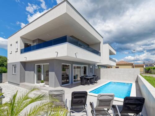 a white house with a swimming pool and chairs at Villa Kana in Umag
