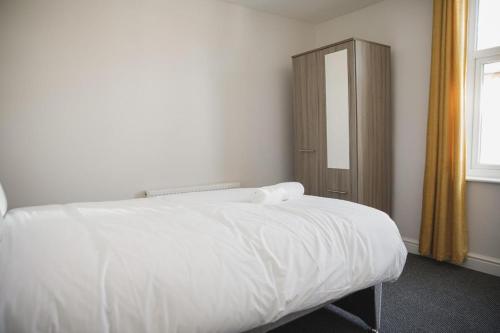 a bedroom with a white bed and a wooden cabinet at Luxury City Rooms in Leicester in Leicester