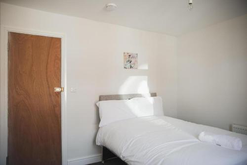 sypialnia z białym łóżkiem i drewnianymi drzwiami w obiekcie Luxury City Rooms in Leicester w mieście Leicester
