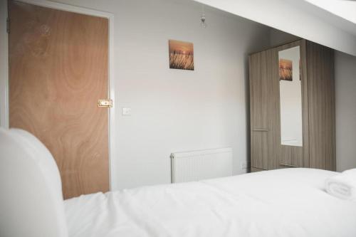sypialnia z białym łóżkiem i lustrem w obiekcie Luxury City Rooms in Leicester w mieście Leicester